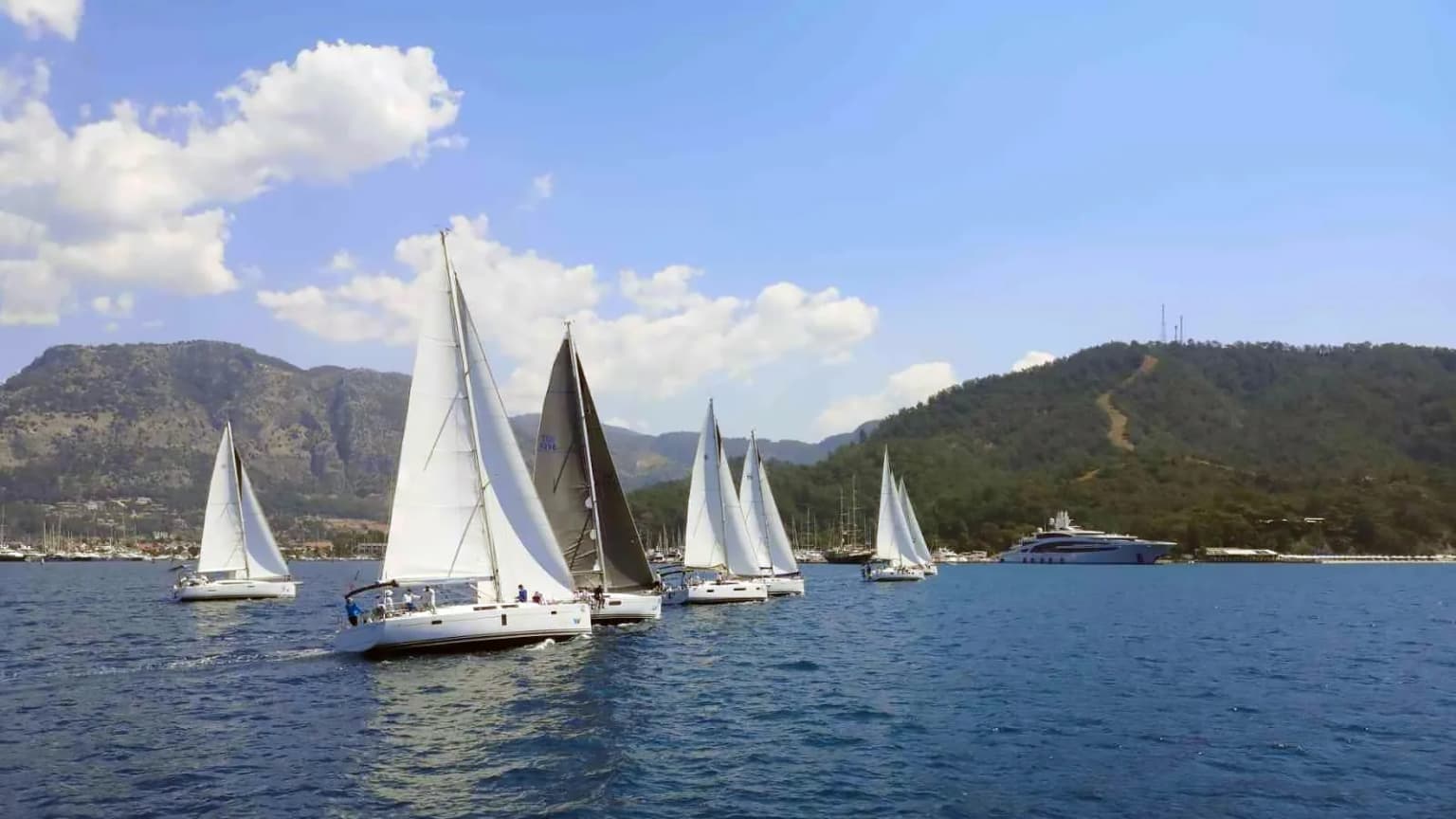 Das Emblem des Göcek Yacht Clubs (GYC) und ein Moment aus einem Segelrennen. Der Club, der den Segelsport und Regatten in Göcek, dem Segelparadies der Türkei, organisiert.