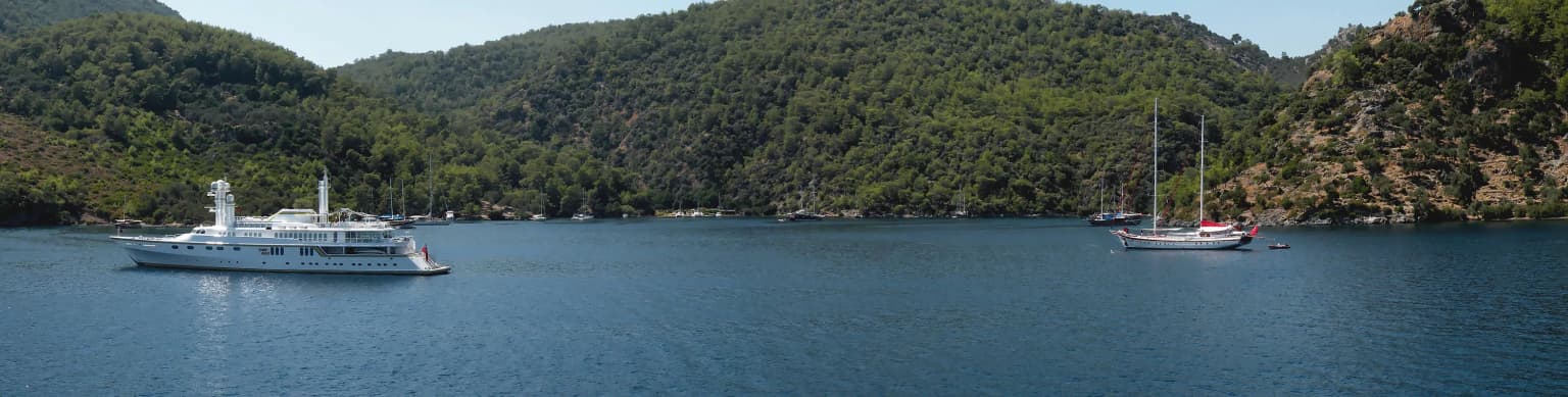 Göcek Yaşyaka Koyu'nun turkuaz sularında demirlemiş mavi yolculuk guletleri ve tekneleri.