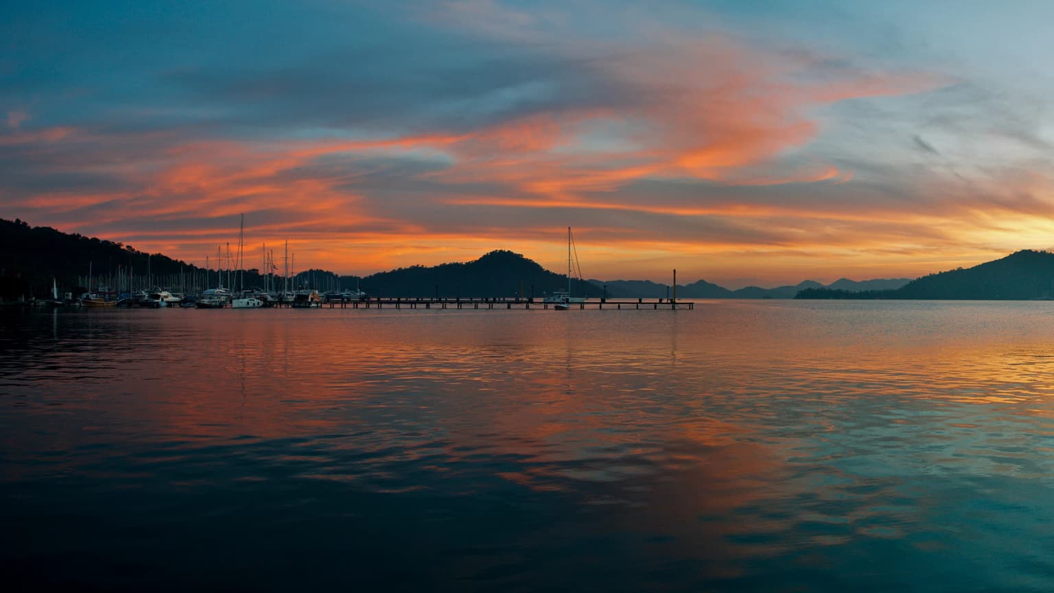 Sonnenuntergang in Göcek; die untergehende Sonne über dem Meer und die Silhouetten der Boote. Ein romantischer und friedlicher Abendmoment im Jachthafen und den Buchten.