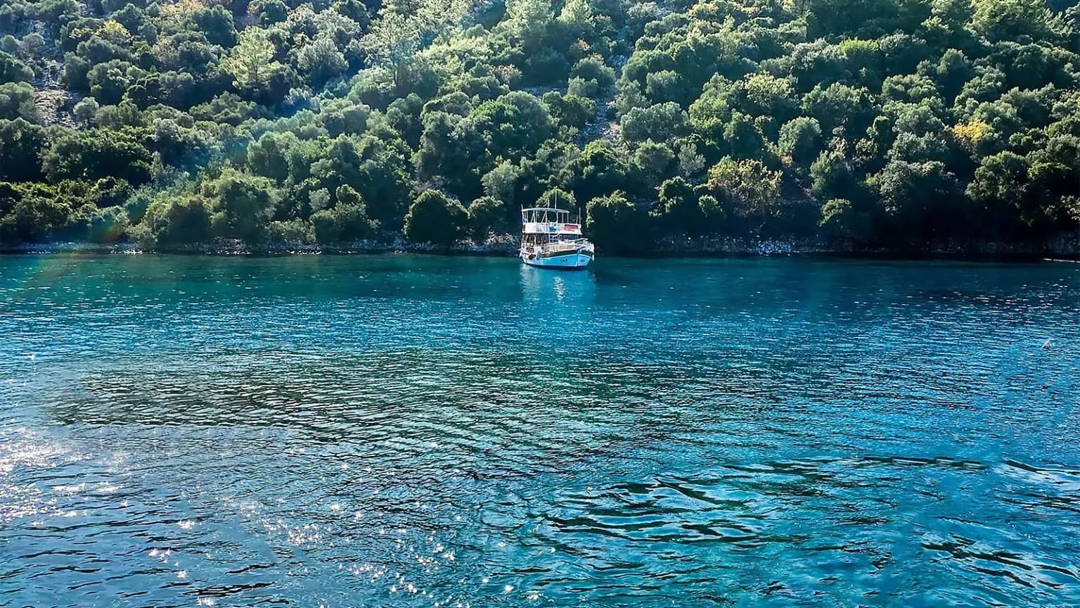 The crystal-clear waters and boats of Aquarium Bay (Akvaryum Koyu) in Gocek. A popular stop on blue cruises for snorkeling and swimming.