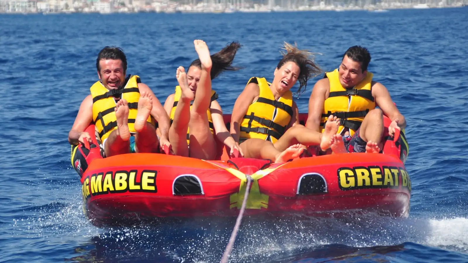 Urlauber, die auf einem von einem Schnellboot gezogenen „Great Big Mable“ in den türkisfarbenen Gewässern von Göcek Spaß haben. Eine adrenalingeladene und unterhaltsame Wassersportaktivität.