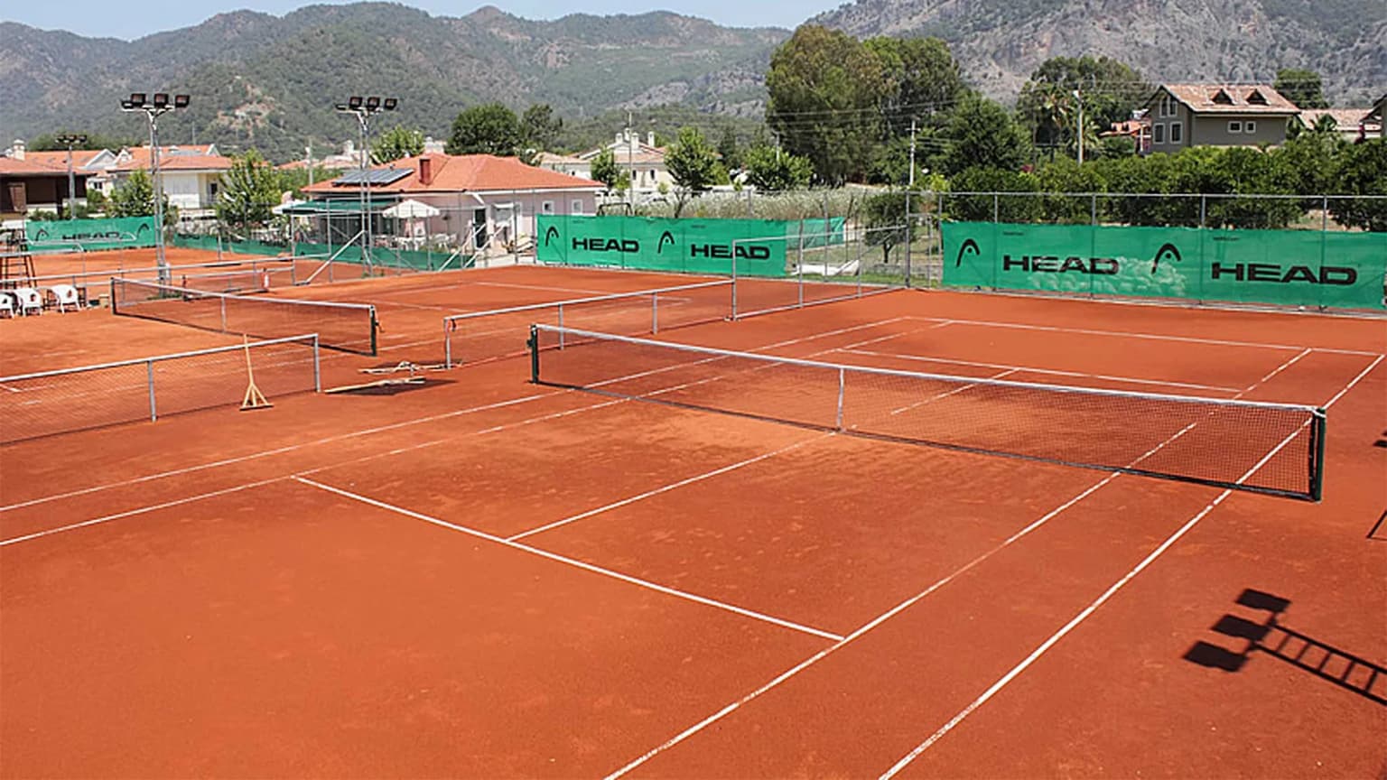Well-maintained clay tennis courts in Gocek with a mountain view in the background. A facility offering sports and recreation for holidaymakers and locals.