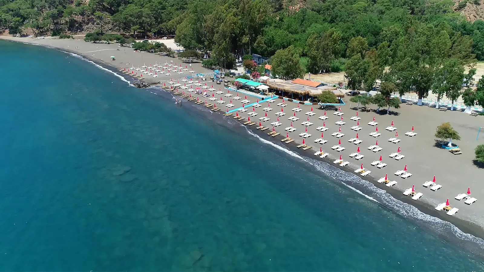 Göcek yakınlarındaki İnlice halk plajının genel görünümü. Çam ağaçlarının denize kadar uzandığı, koyu renkli kumları ile bilinen sakin ve doğal plaj.