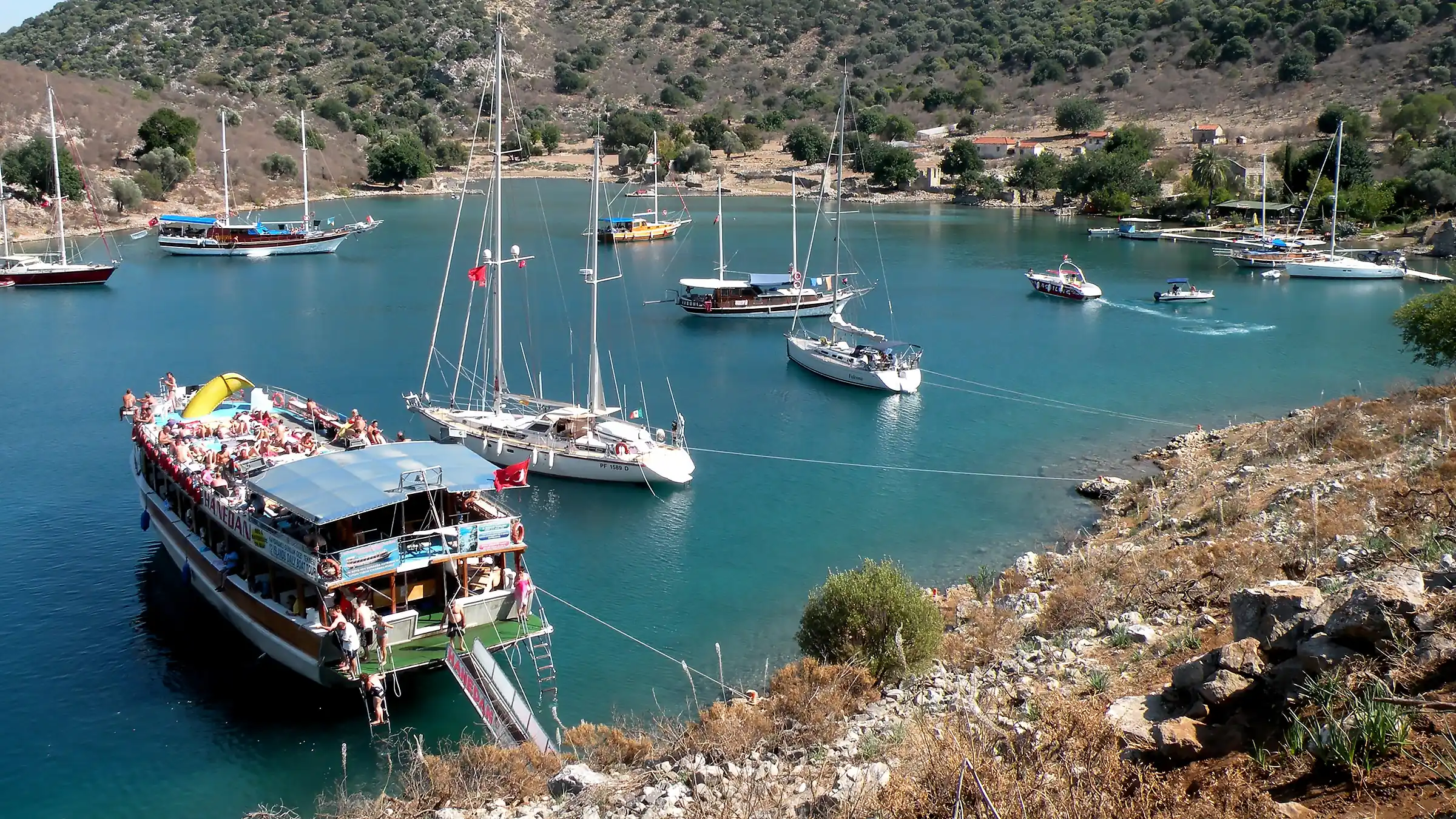 Göcek Tersane Adası'nın Kışlık Koyu'nda demirlemiş bir pazar günü tur teknesi. Mavi yolculuk teknelerinin ve günübirlik turların uğrak noktası olan tarihi koy.