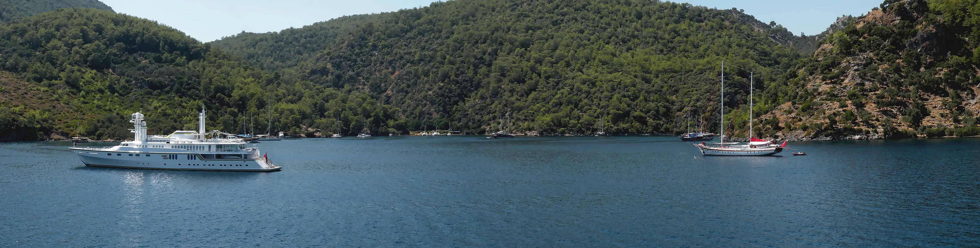 Göcek Yaşyaka Koyu'nun turkuaz sularında demirlemiş mavi yolculuk guletleri ve tekneleri.