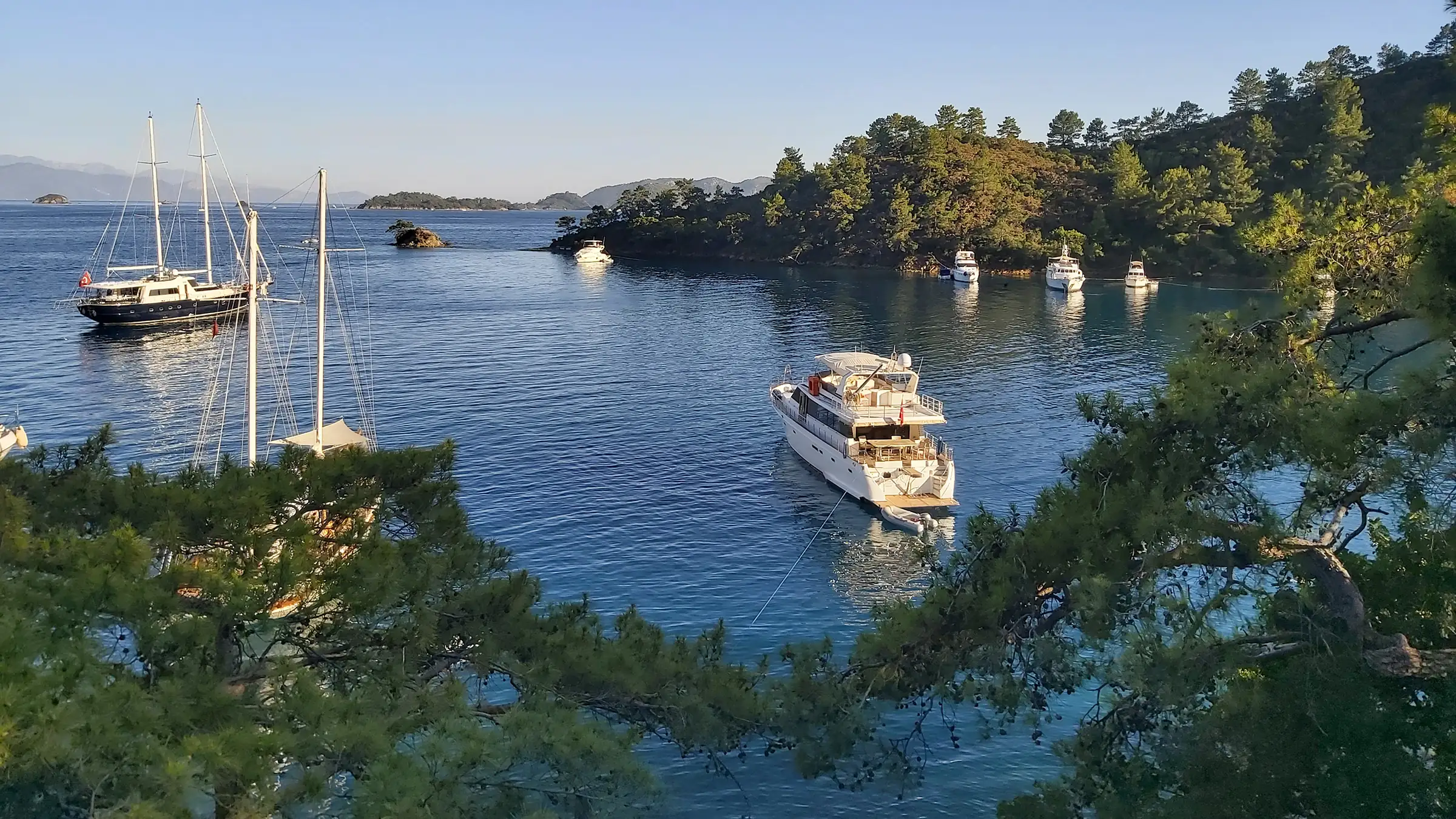 Göcek'teki Osmanağa Koyu'nun yemyeşil doğası ve sakin turkuaz denizi. Tekne turları ve yatların demirlemek için tercih ettiği huzurlu koylardan biri.