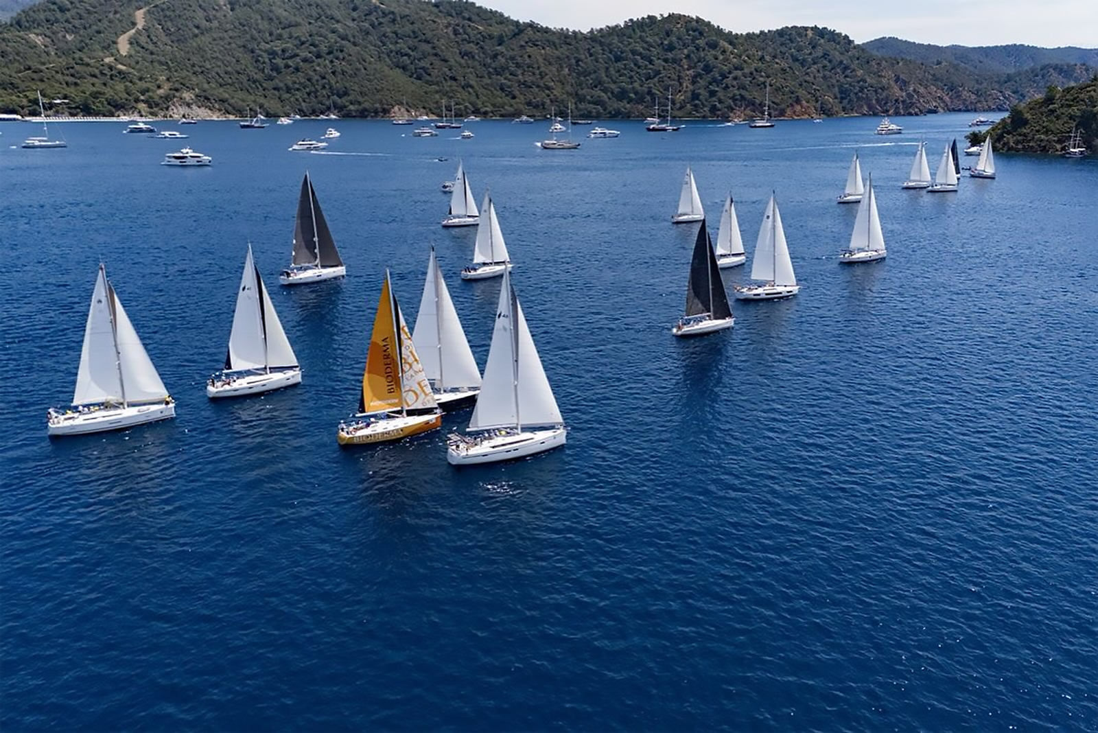 Göcek Yat Kulübü (GYC) tarafından düzenlenen 19 Mayıs Kupası 2025 yelken yarışlarından bir an. Göcek'in eşsiz koylarında yarışan yelkenlilerin mücadelesi.