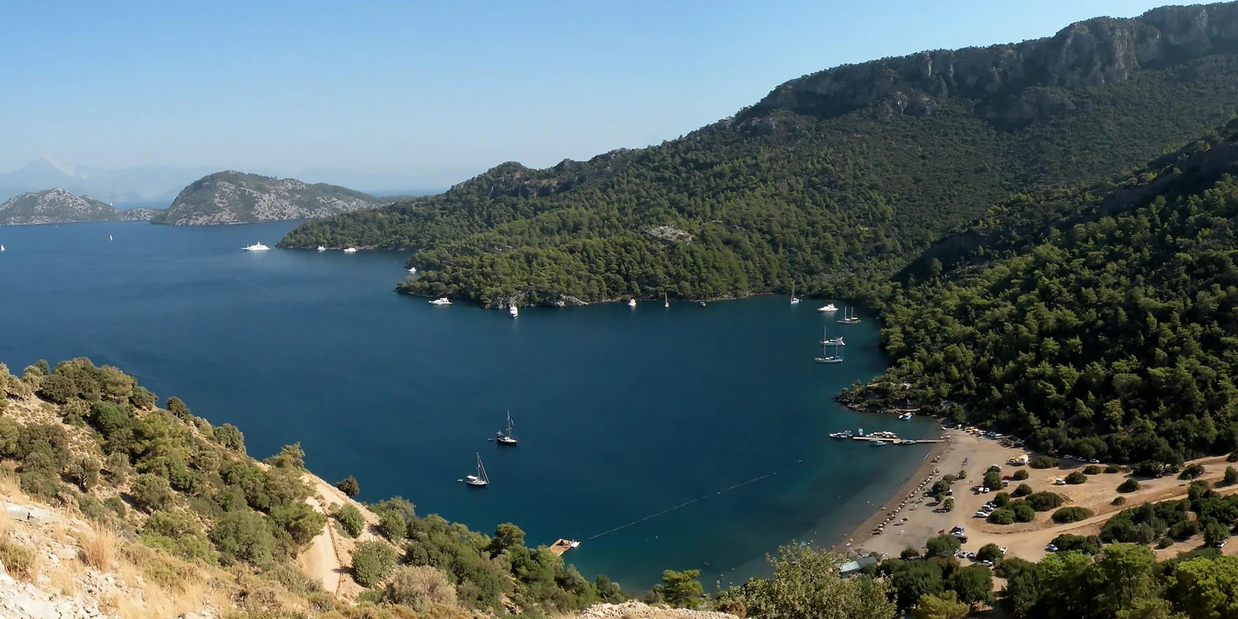 Dalaman'daki Sarsala Koyu'nun tepeden görünümü; plajı, iskelesi ve turkuaz denizi. Göcek'ten araba ve tekneyle ulaşılabilen popüler koy.
